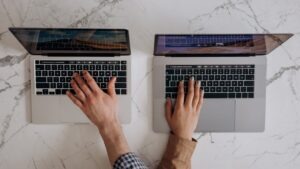 Two small business owners using AI tools on laptops side by side, representing the ChatGPT vs Claude comparison for small businesses