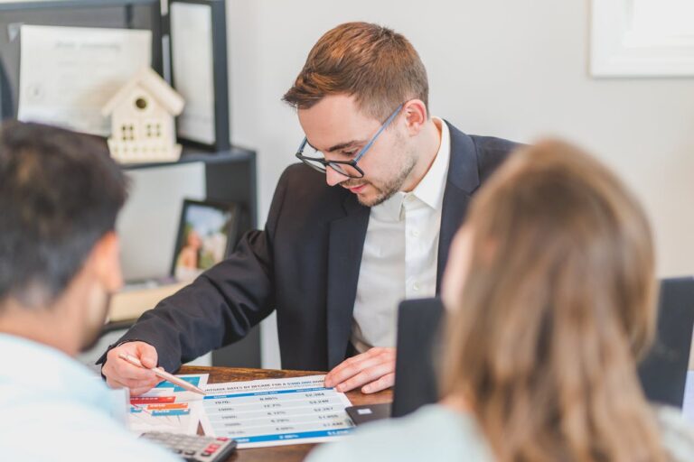 Financial advisor reviewing documents and charts with a client at a desk in a professional office setting