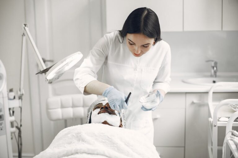 Clean, modern med spa treatment room with a reclining chair, soft lighting, and skincare equipment on a white countertop