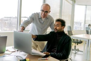 Two business professionals collaborating on a laptop in a bright modern office, representing AI knowledge base setup for small business owners