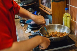 Pro-How AI helps small business owners keep their marketing human and authentic: home cook preparing a real dish in a wok in a home kitchen